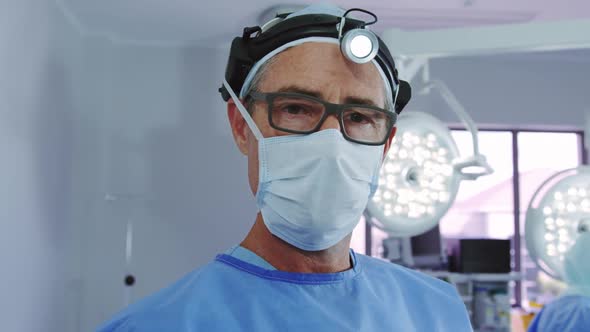 Close-up of Caucasian male doctor standing in surgical headlamp at operation theater in hospital