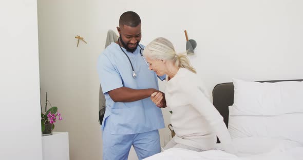 Video of happy african american male doctor taking care of caucasian senior woman