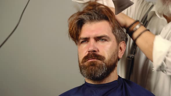 Closeup of Stylist Hipster Man with Hair Dye and Brush Coloring Hair at Barbershop