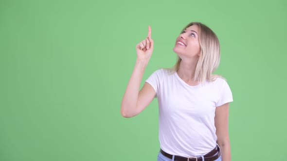 Happy Young Beautiful Blonde Woman Pointing Up and Looking Excited