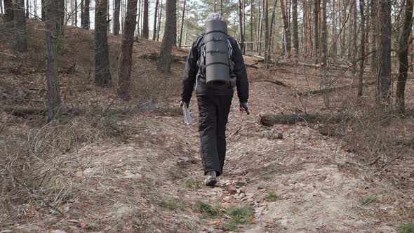 Orienteering in the forest. Tourist on a hike in a forest park with a map.