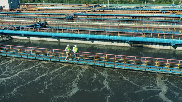 Two Wastewater Operators Walking Along the Water Cleaning Facility