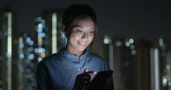 Woman Check on Cellphone in City at Night