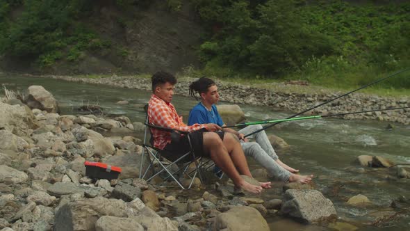 Positive Multiracial Male Travelers Enjoying Leisure and Fishing in Mountain River on Trek