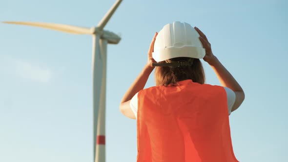 Woman Engineer Takes Off Her Helmet After Work at the Station with Windmills