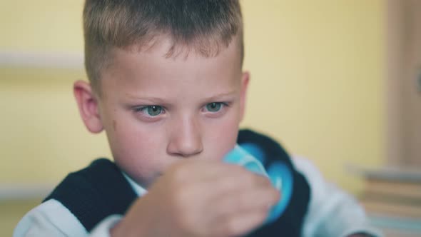 Little Boy Plays with Turning Toy at Break in Classroom