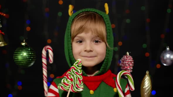 Child Kid Girl in Christmas Elf Santa Claus Helper Costume Licking Candy Lollipop Caramel Sweets