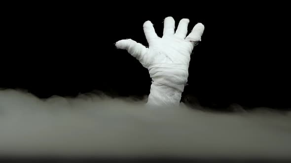 Terrible Mummy Hand Rising Out From the Smoke at Black Background. Slow Motion