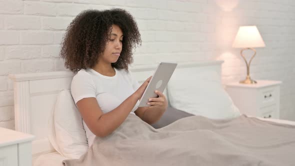 Relaxing Young African Woman Using Tablet in Bed