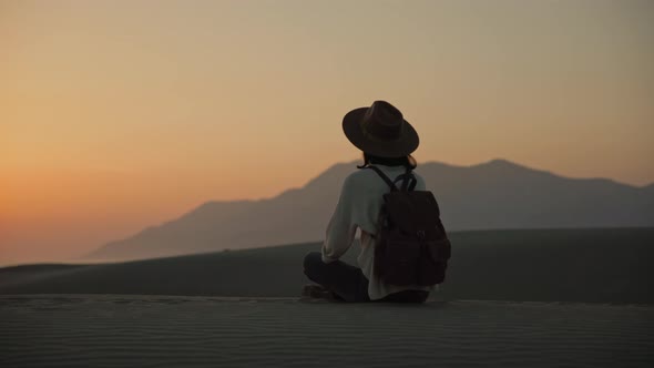 Young woman sitting on the sand and looking at the sea