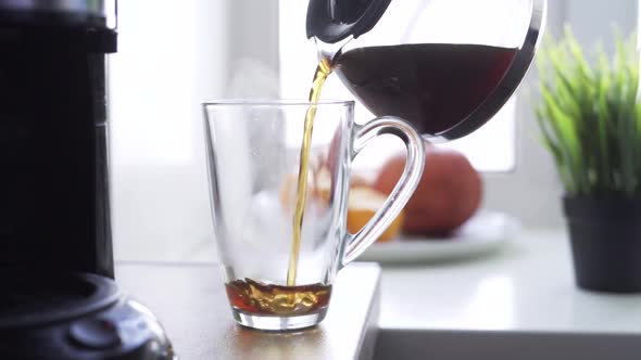 Fresh Coffee Pouring From Turk Into Transparent Cup on Table