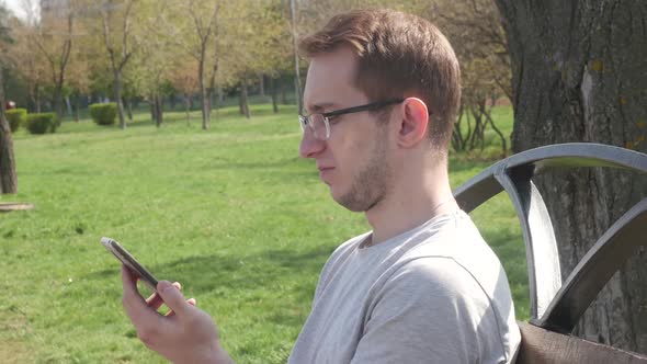 Man In The Park Uses A Smartphone