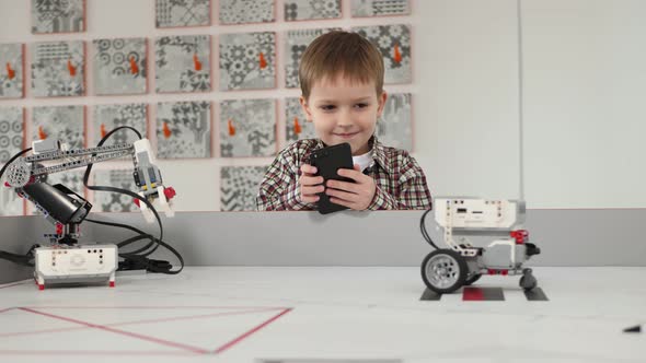 Little Boy Controls a Robot Using His Phone in a Robotics Class