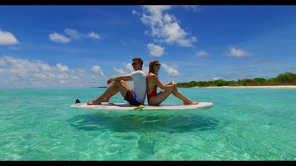 Boy and girl in love on tranquil coastline beach vacation by blue lagoon with white sand background 