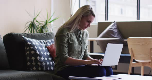 Caucasian businesswoman sitting and using her laptop in modern office