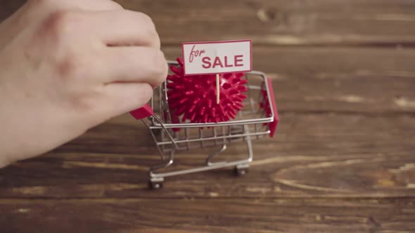 Small Shopping Cart with Coronavirus Shaped Ball on Table