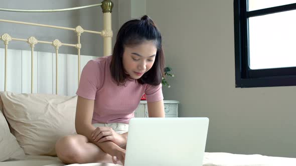 Asian Young Girl Using Her Laptop in the Bedroom