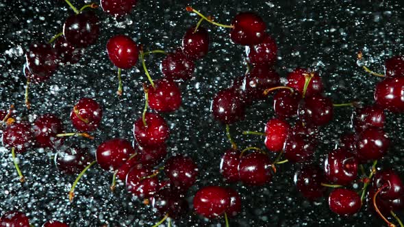 Super Slow Motion Shot of Flying Fresh Cherries and Water Side Splash at 1000Fps.