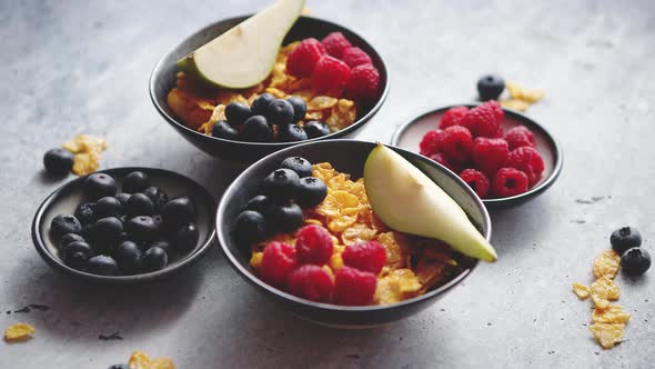 Golden Cornflakes with Fresh Fruits of Raspberries Blueberries and Pear in Ceramic Bowl