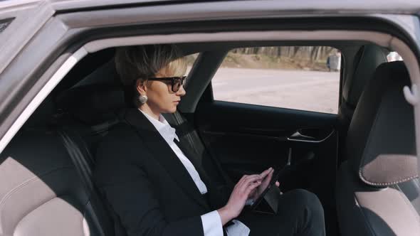 A Businesswoman in Glasses Is Working in a Car