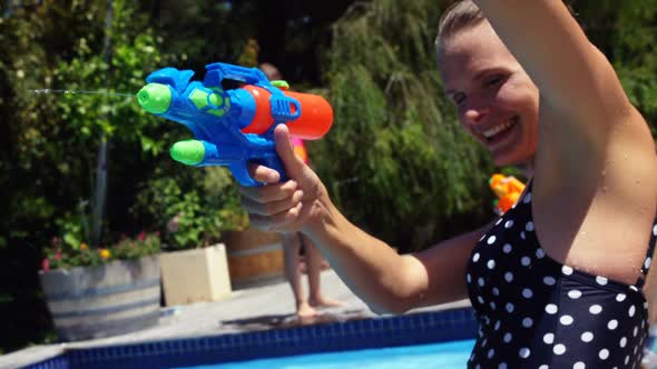 Happy family doing water gun battle in swimming pool