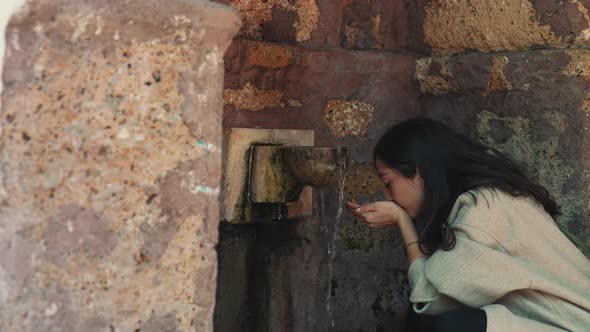 Woman Drinking Water in Historical Fountain