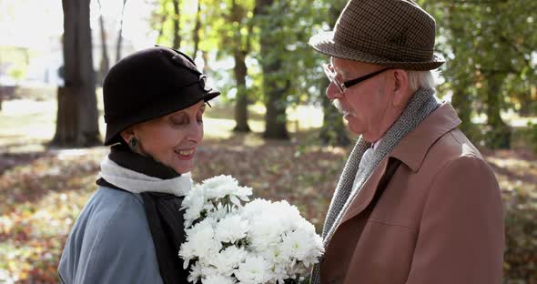 Senior Gentleman Presents a Bouquet of Flowers to His Woman She Rejoices