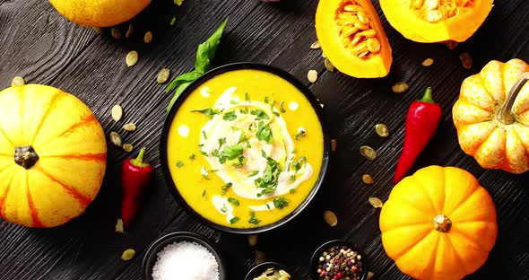 Yellow Fresh Pumpkin Soup Surrounded By Spices and Seeds