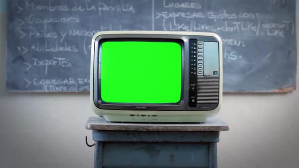 Man Hand with Remote Control turning On an Old TV Set Green Screen in Class. 4K Version.