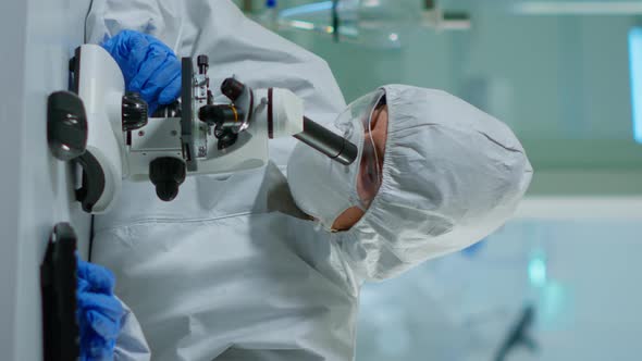 Vertical Video Biologist Doctor in Coverall Checking DNA Sample on Microscope