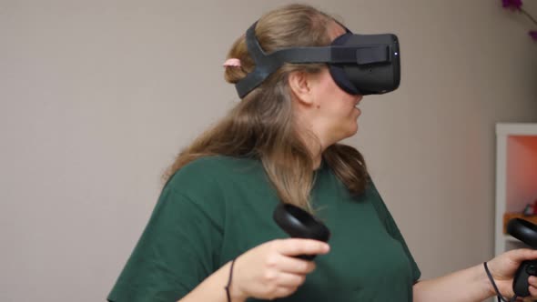 A girl in a virtual reality helmet with controllers in her hands walks around the meta universe