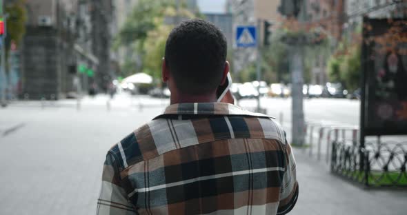 Rear Back View of African American Young Man Talking Phone Walk on City Streets