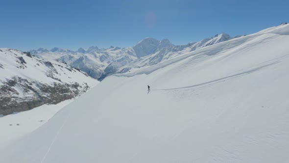 Aerial Follow View Active Freerider Riding Skiing on Top Ridge Downhill