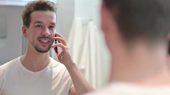 Young Man Talking on Smartphone in Mirror