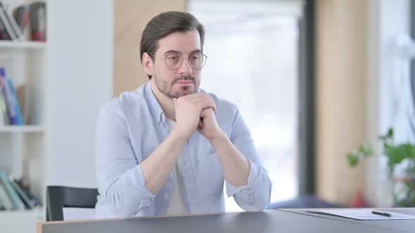 Man in Glasses Sitting in Office Thinking