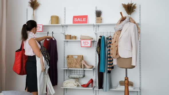 Shopaholic Woman Grabbing Lot of Clothes on Sale