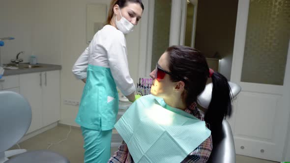 Young Woman in Red Protective Glasses Rinsing Her Mouth with Treatment at the Dentist
