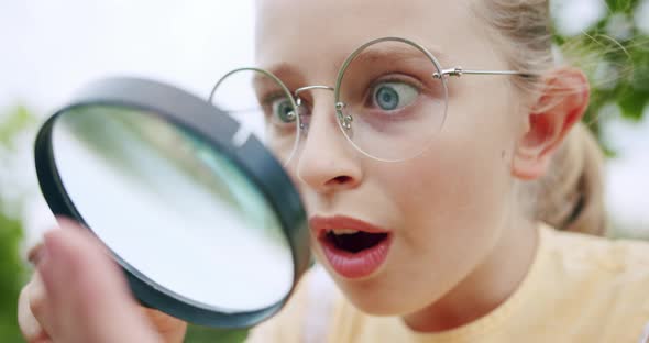 A Teenage Girl Looks Through the Magnifying Glass at the Micro World of Insects