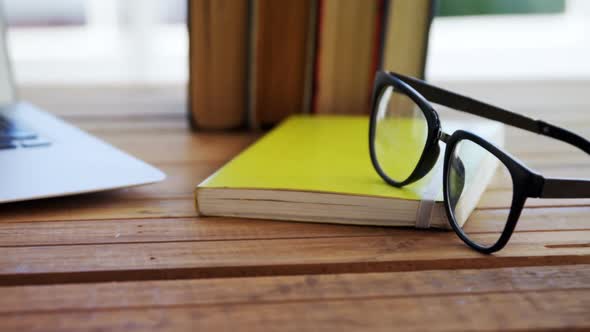 Laptop, books and spectacles on wooden table 4k