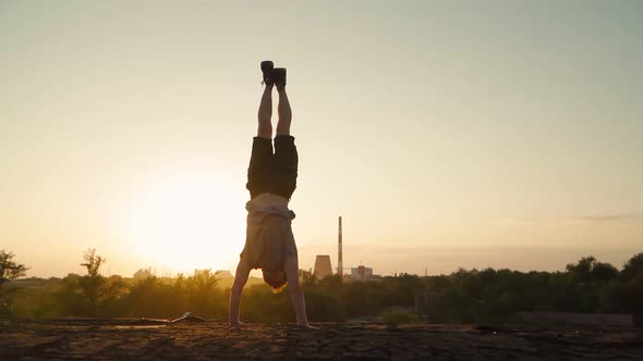 Cool man doing a handstand against the backdrop of a beautiful sunset. Sports and motivation.