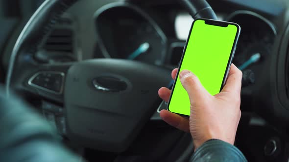 Driver Using a Smartphone Inside the Car. Chromakey Smartphone with Green Screen. Auto Navigation