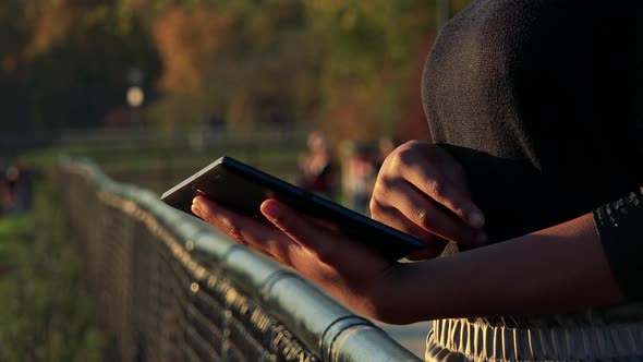 Young Black Woman Works on Tablet - Park in the Background - Closeup