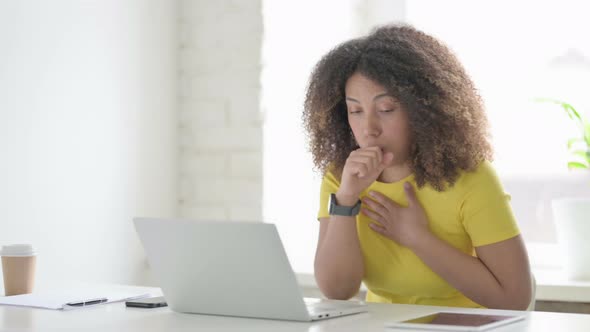 African Woman Coughing while using Laptop in Office