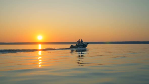 Fishing Autoboat Is Slowly Sailing Across Water with Two Men in It