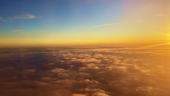 Flying Under the Clouds Illuminated in Orange By the Suns Rays at Sunset