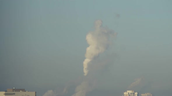 City Pipes Emit Steam Into the Atmosphere Against the City Skyline 7