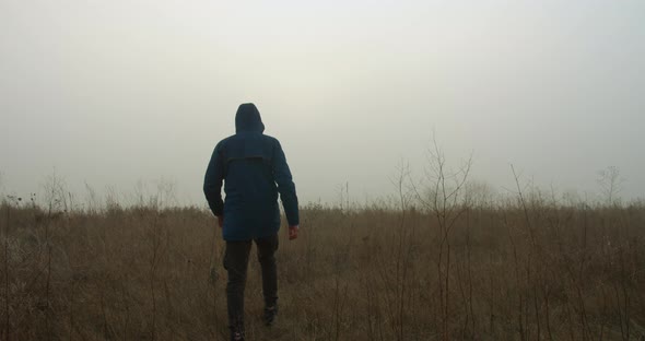 Mysterious Video. The Guy Is Wearing a Hood and Walking Through a Foggy Field. 