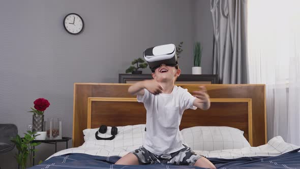Small Boy in Homewear Being in Bedroom and Playing Video Game Using Special Virtual 3d Goggles