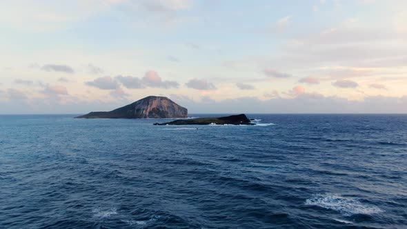 Drone flying toward mini islands in hawaii during a beautiful sunrise