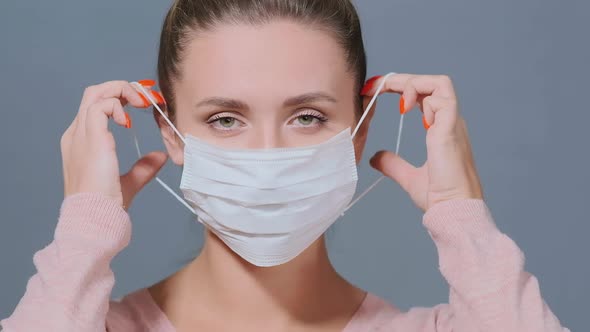 Brunette Puts White Disposable Mask on Ears and Fixes